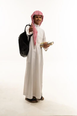 علامة الجودة والامتيازوالتميز، بورتريه لطالب عربي خليجي سعودي يرتدي الثوب التقليدي و الشماغ يحمل حقيبة الظهر و الكتب الدراسية يشير بيده بإيماءات وتعابير وجه و يدين تدل على الاعجاب، التعبير عن الجودة والاتقان، القبول والموافقة والرضا، صورة الجسم بالطول الكامل، خلفية بيضاء