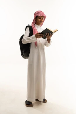 Developing reading skills, spending leisure time on education and learning, paying attention to browsing useful books, a portrait of an Arab Saudi Gulf student wearing traditional thobe and ghutrah with a backpack holding a book in hand, full-body, white background.