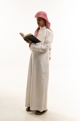 حب المطالعة والقراءة, قضاء أوقات الفراغ بالتثقيف والتعلم, تنمية مهارات القراءة, الاهتمام بتصفح الكتب المفيدة, , بورتريه لولد عربي سعودي خليجي يرتدي الثوب والشماغ التقليدي يمسك بيده كتاب, الجسم بالطول الكامل، خلفية بيضاء