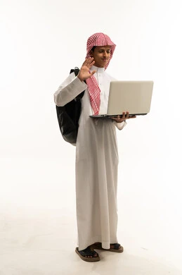 التواصل عبر الفيديو على الكمبيوتر المحمول، تعابير الترحيب والاستقبال، مفهوم التعليم عن بعد، بورتريه لطالب عربي خليجي سعودي يرتدي الثوب التقليدي و الشماغ و حقيبة الظهر يستخدم الحاسب المحمول في البحث والمطالعة وتصفح التطبيقات الالكترونية، الجسم بالطول الكامل، خلفية بيضاء