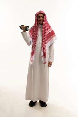 نشاط بدني للمحافظة على الصحة و اللياقة الجسدية، تقوية عضلات الجسم و بنائها ، بورتريه لصبي عربي خليجي سعودي يرتدي الثوب التقليدي و الشماغ يقوم بممارسة التمارين الرياضية مع الدمبل ،رفع الأوزان الحديدية الثقيلة ، صوره الجسم بالطول الكامل ، خلفيه بيضاء