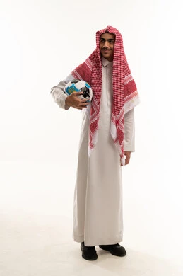 الشغف في متابعه الفرق وتشجيع المنتخبات،  بورتريه لولد عربي خليجي سعودي يرتدي الثوب التقليدي و الشماغ  يحمل كرة قدم  و ينظر الى شيء ما ،الجسم بالطول الكامل، خلفية بيضاء