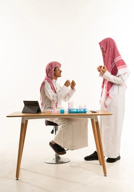 أجواء من المرح داخل المعمل، بورترية لطالبان عربيان خليجيان سعوديان يقضيان وقت ممتع في معمل الكيمياء، إستخدام انابيب الاختبار لإجراء التجارب، إستخدام الجهاز اللوحي ، تجارب وأبحاث علمية، خلفية بيضاء