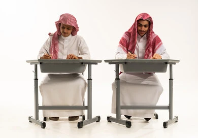 التعليم الدراسي في المملكة العربية السعودية، إيماءات الاجتهاد والتفوق, بورترية لطالبان عربيان خليجيان سعوديان يرتديان الثوب الابيض و الشماغ يجلسان على الطاولة يقومان بمراجعة الدروس للمذاكرة والاختبارات المدرسية، خلفية بيضاء