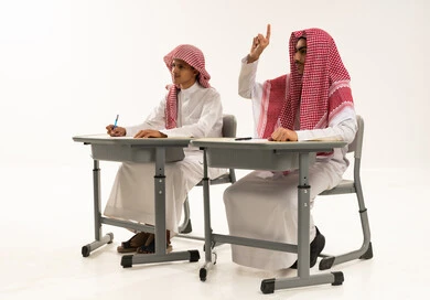 المشاركة الفعالة خلال شرح الدروس، تعابير وايماءات الحماس لمعرفة الجواب الصحيح، تأدية الواجبات المدرسية، ورترية لطالبان عربيان خليجيان سعوديان يرتدين الثوب الابيض و الشماغ يجلسان على الطاولة فى الفصل، التربية والتعليم بالمناهج المقررة للطلاب في المملكة العربية السعودية، خلفية بيضاء