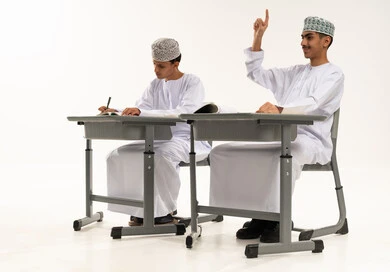 تأدية الواجبات المدرسية، المشاركة والتفاعل داخل الفصل الدراسي، بورترية لطالبان عربيان خليجيان عمانيان يرتديان الدشداشة و الكمة يجلسان على الطاوله فى الفصل، التربية والتعليم بالمناهج المقررة للطلاب في سلطنه عمان ، تعابير وايماءات الحماس لمعرفة الجواب الصحيح، خلفية بيضاء