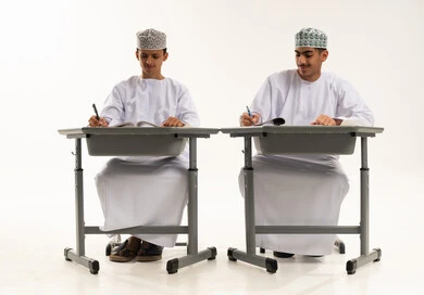 مراجعة الدروس الدراسية، المذاكرة للإختبارات المدرسية، بورتريه لطالبان عربيان خليجيان عمانيان يرتديان الدشداشة و الكمة يجلسان على الطاولة يقومان بتأدية الواجبات المدرسية، الإستعداد للعام الدراسي الجديد، التعليم الدراسي في سلطنه عمان، العودة إلى المدارس، خلفية بيضاء