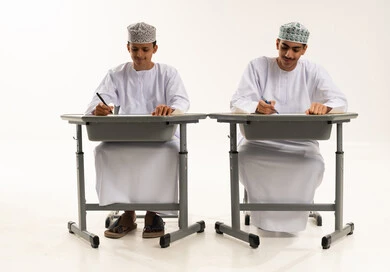 ايماءات الاندماج و التركيز، المذاكرة للإختبارات المدرسية، بورتريه لطالبان عربيان خليجيان عمانيان يرتديان الدشداشة و الكمة يجلسان على الطاولة يقومان بتأدية الواجبات المدرسية، مراجعة الدروس الدراسية، الإستعداد للعام الدراسي الجديد، التعليم الدراسي في سلطنه عمان، العودة إلى المدارس، خلفية بيضاء