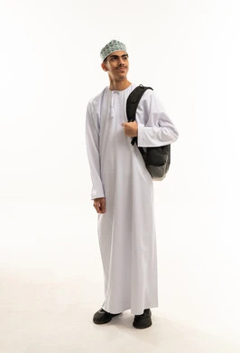 Back to school season, academic education in educational institutions in the Sultanate of Oman, a portrait of an Arab Gulf Omani student wearing a dishdasha and kumma, carrying a backpack and looking at something, full body, white background.
