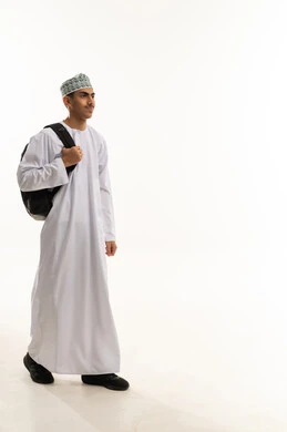 The concept of back to school, gestures of walking and going to a specific place, educational scientific curricula, a portrait of an Arab Gulf Omani student wearing a dishdasha and kumma carrying a backpack, looking with gestures of happiness and joy, full-body image, white background.