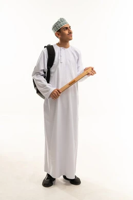 قياس المسافات ورسم الخطوط المستقيمة بالمسطرة الخشبية، بورتريه لطالب ثانوي عربي خليجي عماني يرتدي الدشداشة و الكمة و حقيبة الظهر ينظر الى شيء ما، أهمية التعليم في بناء مستقبل مشرق للمجتمع العمانى ، صورة الجسم بالطول الكامل، خلفية بيضاء