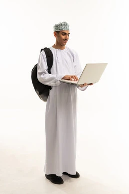 ايماءات الاندماج و التركيز، مفهوم التعليم عن بعد، بورتريه لطالب عربي خليجي عماني يرتدي الكمه والدشداشه و حقيبة الظهر يستخدم الحاسب المحمول في البحث والمطالعة وتصفح التطبيقات الالكترونية، الجسم بالطول الكامل، خلفية بيضاء