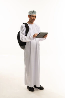 التعليم الجامعي في سلطنه عمان، مراجعة الدروس اليومية , استخدام الأجهزة التقنية الحديثة, بورتريه لطالب جامعي عربي خليجي عماني يرتدي الدشداشة و الكمة يحمل حقيبة على ظهره وبيده الجهاز اللوحي, الجسم بالطول الكامل, خلفية بيضاء