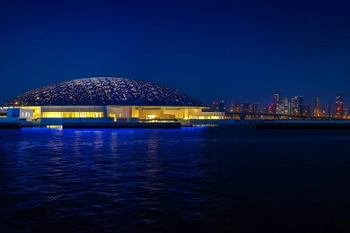 Famous tourist places and landmarks in the United Arab Emirates, distinctive designs and decorations, the architectural art of modern towers and skyscrapers, a futuristic Emirati vision, the Louvre Museum overlooking the Arabian Gulf coast at night in the Emirate of Dubai