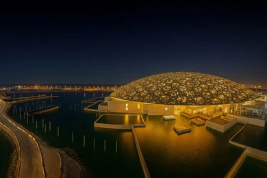 Famous tourist places and landmarks in the United Arab Emirates, distinctive designs and decorations, the architectural art of modern towers and skyscrapers, a futuristic Emirati vision, the Louvre Museum overlooking the Arabian Gulf coast at night in the Emirate of Dubai
