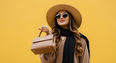 Keeping up with modern fashion designs and styles, a close-up portrait of a Saudi Arabian Gulf girl wearing casual clothes, a hat, sunglasses and holding a leather bag with feminine and gentle gestures, marketing Saudi products and luxury international brands, yellow background