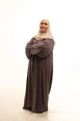 مفهوم الاناقه و الاهتمام بالمظهر الخارجي، النظر إلى الكاميرا بإيماءات السرور والثقة بالنفس، ورترية لإمراة كبيرة بالسن عربية سعودية خليجية محجبة ترتدي العباءة تقف بأيدي متقاطعه، صورة الجسم بالطول الكامل، خلفية بيضاء