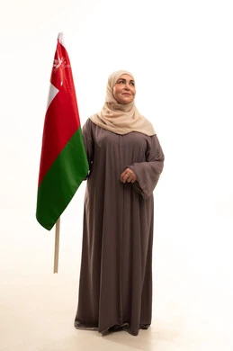 ثقافات ورموز وطنية، إحياء ذكرى تأسيس الدولة 1775 م، حب الوطن والانتماء إليه, بورترية لإمراة كبيرة بالسن عربية عمانية خليجية محجبة ترتدي العباءة تمسك العلم الوطني للبلاد تحتفل بذكرى اليوم الوطني العماني 18 نوفمبر، الجسم بالطول الكامل، خلفية بيضاء