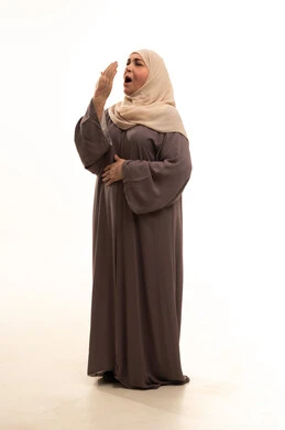 السهر لوقت متأخر, النعاس والارهاق والحاجة إلى النوم, الشعوربالكسل والخمول وطلب الراحة, بورترية لإمراة كبيرة بالسن عربية سعودية خليجية محجبة ترتدي العباءة تضع يدها على فمها تقوم بالتثاؤب, الجسم بالطول الكامل، خلفية بيضاء