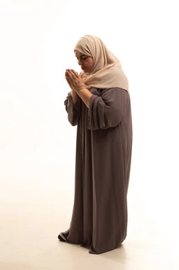 Supplication and seeking help from God, the concept of asking for assistance, the desire to fulfill wishes, a portrait of an elderly Arab Saudi Gulf woman wearing a hijab and an abaya, raising her hands in gestures of asking for help, full-body, white background.