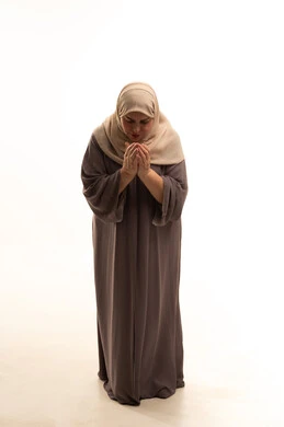 مفهوم طلب العون، التضرع و التوسل إلى الله، الرغبه في تحقيق الأمنيات،  بورترية لإمراة كبيرة بالسن عربية سعودية خليجية محجبة ترتدي العباءة ترفع يديها بايماءات طلب المساعدة، الجسم بالطول الكامل، خلفية بيضاء