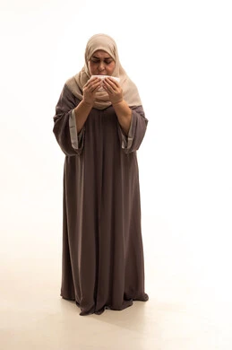 التعرض للإصابة بفيروس كوفيد-19، الشعور بالتعب والمرض، بورترية لإمراة كبيرة بالسن عربية سعودية خليجية محجبة ترتدي العباءة تقوم باستعمال المناديل الورقية أثناء العطس، إيماءات وجه ويدين تدل على العطاس، الجسم بالطول الكامل, خلفية بيضاء