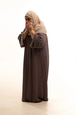 التعرض للإصابة بفيروس كوفيد-19، الشعور بالتعب والمرض، بورترية لإمراة كبيرة بالسن عربية سعودية خليجية محجبة ترتدي العباءة تقوم باستعمال المناديل الورقية أثناء العطس، إيماءات وجه ويدين تدل على العطاس، الجسم بالطول الكامل, خلفية بيضاء