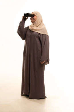 حب الاستكشاف والمغامرة، رؤية الأشياء البعيدة، بورترية لإمراة كبيرة بالسن عربية سعودية خليجية محجبة ترتدي العباءة تمسك منظار ثنائي العينين، التخطيط المستقبلي للأهداف والطموحات، الجسم بالطول الكامل، خلفية بيضاء