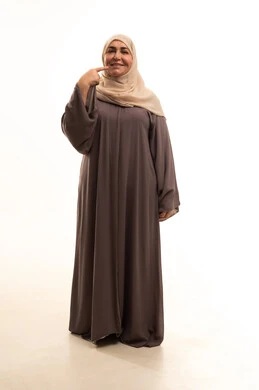 إشارات وحركات يدين تدل على هذا المكان (هنا)، تعابير السرور والفرح، تحديد موقع معين بإيماءات البشاشة، بورترية لإمراة كبيرة بالسن عربية سعودية خليجية محجبة ترتدي العباءة تشير الى شيء ما،الجسم بالطول الكامل، خلفية بيضاء