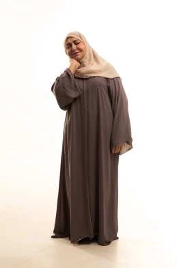 آلام العنق والعمود الفقري, وجع مفاصل و عظام الرقبة, الحاجة للعلاج الفيزيائي، الإحساس بالتعب والإرهاق, بورترية لإمراة كبيرة بالسن عربية سعودية خليجية محجبة ترتدي العباءة تضع يديها حول عنقها بإيماءات الألم, الجسم بالطول الكامل, خلفية بيضاء