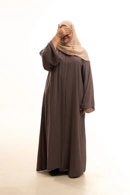 ايماءات إغماض العينين وانتظار رؤية المفاجأة، بورترية لإمراة كبيرة بالسن عربية سعودية خليجية محجبة ترتدي العباءة تضع يديهاعلى وجهها بتعابير تدل على البكاء والحزن، الجسم بالطول الكامل، خلفية بيضاء