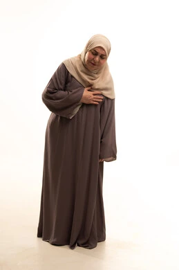 مشاكل صحية صعبة، الذبحه الصدريه حالة مرضية، إيماءات التعب والإرهاق والضغوطات النفسية، بورترية لإمراة كبيرة بالسن عربية سعودية خليجية محجبة ترتدي العباءة تضع يدها على قلبها تشعر بحالة سيئة من الوخز والألم, الجسم بالطول الكامل، خلفية بيضاء