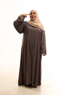 إشارات وحركات يدين تدل على هذا المكان (هنا)، تحديد موقع شيء معين،  بورترية لإمراة كبيرة بالسن عربية سعودية خليجية محجبة ترتدي العباءة تشير بإصبع السبابة إلى جهة اليمين، صورة الجسم بالكامل، خلفية بيضاء