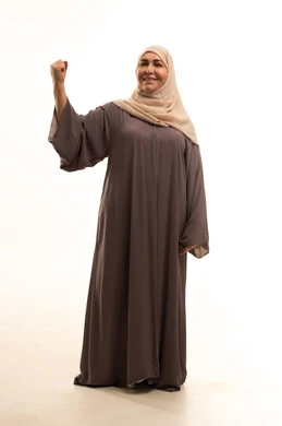 الفرح بالنصر والفوز، تحقيق الأهداف والنجاح، بورترية لإمراة كبيرة بالسن عربية سعودية خليجية محجبة ترتدي العباءة ترفع قبضة يديها بإيماءات الحماس والانتصار، تعابير السعادة و السرور، الجسم بالطول الكامل، خلفية بيضاء