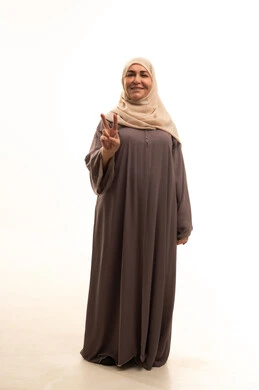 Success and achieving goals, expressions of joy and happiness, a portrait of an elderly Arab Saudi Gulf woman wearing a hijab and an abaya, looking at the camera with facial and hand gestures indicating victory and triumph, full-body, white background.