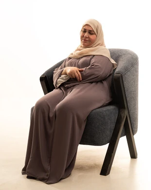 التأمل والتمعن والاندماج, بورتريه لإمرأة كبيرة بالسن عربية خليجية سعودية محجبة ترتدي العباءة تجلس على الكرسي بايماءات وجه ويدين مختلفة، الثقة بالنفس والراحة النفسية، خلفية بيضاء