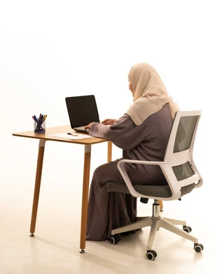 Accomplishing tasks and work, integrating modern technologies and technology into practical life, the concept of remote work, and a side portrait of an elderly Arab Gulf Saudi woman wearing an abaya and hijab sitting at a table using a laptop, with a white background. Accomplishing tasks and work, integrating modern technologies and technology into practical life, the concept of remote work, and a side portrait of an elderly Arab Gulf Saudi woman wearing an abaya and hijab sitting at a table using a laptop, with a white background.