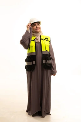 Standing with confident gestures, the concept of engineering project management, women's jobs and professions, a portrait of an elderly Saudi Gulf Arab female engineer wearing a hijab, wearing a safety vest and helmet, looking at something, full-body image, white background.