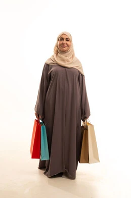 Looking at the camera with gestures of joy and happiness, shopping and buying supplies and gifts, getting offers and discounts, a portrait of an elderly Saudi Gulf Arab woman wearing an abaya and hijab holding shopping bags in her hands, a full-body image, white background. Looking at the camera with gestures of joy and happiness, shopping and buying supplies and gifts, getting offers and discounts, a portrait of an elderly Saudi Gulf Arab woman wearing an abaya and hijab holding shopping bags in her hands, a full-body image, white background.