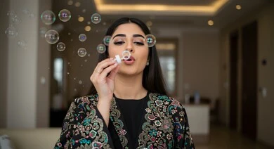 امرأة عربية  سعوديه خليجيه ترتدي عباءه تمسك بيدها لعبة فقاعات الصابون وتقوم بالنفخ فيها , التسليه والترفيه بألعاب الاطفال,  الاستمتاع بالفقاعات الصابونيه