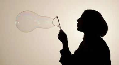 الاستمتاع بصنع فقاعة الصابون في الهواء, قضاء الأوقات بالأنشطة الترفيهية الممتعه والمسلية, اللعب بالفقاعات المائية المتطايرة والمتناثرة، صورة ظلية لامرأة عربية خليجية سعودية تقوم بنفخ فقاعة صابون كبيرة