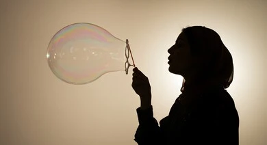 الاستمتاع بصنع فقاعة الصابون في الهواء, قضاء الأوقات بالأنشطة الترفيهية الممتعه والمسلية, اللعب بالفقاعات المائية المتطايرة والمتناثرة، صورة ظلية لامرأة عربية خليجية سعودية تقوم بنفخ فقاعة صابون كبيرة