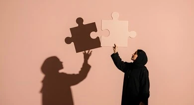 التسلية والترفيه وقضاء وقت ممتع, ألعاب الذكاء وتنمية المهارات, الدقة والتركيز وحل اللغز, بورتريه لسيدة عربية خليجية سعودية محجبة ترتدب عباءة سوداء تحاول ربط وتوصيل قطع البزل, لعبة تركيب الصور، انعكاس الظل على الجدار، خلفية وردية