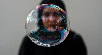 التسليه والترفيه بألعاب الاطفال، الاستمتاع بصنع فقاعة الصابون في الهواء, قضاء الأوقات بالأنشطة الترفيهية الممتعه والمسلية, اللعب بالفقاعات المائية المتطايرة والمتناثرة، صورة مقربة لفقاعة صابون كبيرة عاكسة على امرأة عربية خليجية سعودية