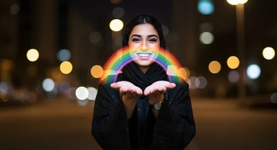 امرأة عربية خليجية سعودية محجبة مبتسمة تحمل بيديها قوس قزح مضيء بإيماءات وتعابير السعادة والسرور، إظهار مشاعر الفرح بقوس الألوان، خلفية الأبراج والمباني المضاءة في وقت الليل امرأة عربية خليجية سعودية محجبة مبتسمة تحمل بيديها قوس قزح مضيء بإيماءات وتعابير السعادة والسرور، إظهار مشاعر الفرح بقوس الألوان، خلفية الأبراج والمباني المضاءة في وقت الليل