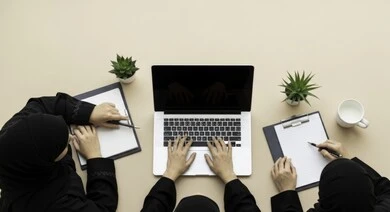 Overhead view of a business meeting between Saudi Arabian Gulf female employees in a conference room. Understanding and cooperation between colleagues to achieve company goals. Comfortable work environment in Saudi companies. Use of modern technical devices in offices. Saudi female office profession and job. Overhead view of a business meeting between Saudi Arabian Gulf female employees in a conference room. Understanding and cooperation between colleagues to achieve company goals. Comfortable work environment in Saudi companies. Use of modern technical devices in offices. Saudi female office profession and job.