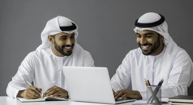  التفاهم والتعاون بين الزملاء لتحقيق أهداف الشركة , إدارة شؤون الأعمال وتنظيمها عبر الاجهزة التقنية، مهن ووظائف ادارية مكتبية، دمج العمل مع التقنية والتكنولوجيا، رجلان عربيان خليجيان اماراتيان يرتديان الكندورة والغتره يقومان بالعمل على الحاسوب داخل المكتب