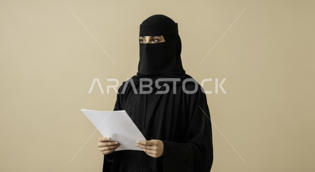 Completing required tasks, following up on correspondence and records, a Saudi Arabian Gulf woman wearing a niqab and abaya holding blank papers in her hands, carefully reading notes and reports, looking at something, following up on plans and reports