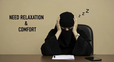 تعابير الكسل والخمول، الحاجة للنوم والراحة، امرأة عربية خليجية سعودية منقبة ترتدي عباءة سوداء تجلس على الكرسي أمام مكتبها تضع يديها على رأسها بإيماءات تدل على النعاس والتعب، السهر لوقت متأخر