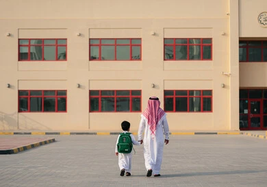 الشعور بالأمان والحب مع الآباء، موسم العودة للمدارس في السعودية، مفهوم الاعتناء بالأبناء والاهتمام بهم، ولد عربي خليجي سعودي يرتدي الزي المدرسي يضع الحقيبة على ظهره ويمسك بيد والده، الاستعداد للعام الدراسي